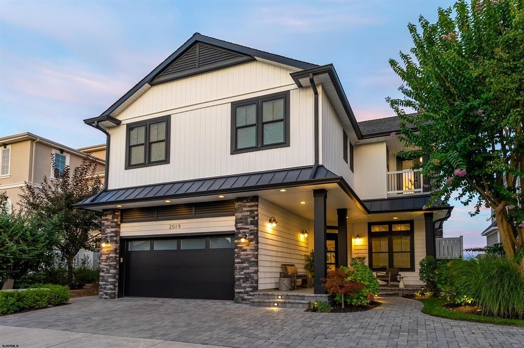 Two-story waterfront home exterior at dusk in the Riviera neighborhood of Ocean City, NJ, with stone accents and covered front porch.
